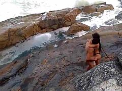 Egy érett afrikai nő természetes mellekkel a tengerpart előtt szar