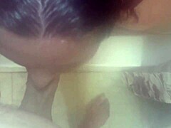 Una mujer de grandes pechos se limpia en la ducha y recibe una eyaculación en la cara