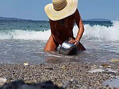 Érett nő kinyújtott mellbimbópiercingekkel és többszörös puncipiercigekkel a tengerparton