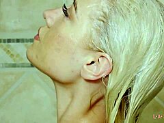 Blonde schoonheid laat haar verleidelijke lichaam zien in een douchescène