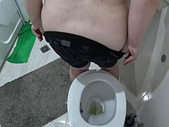 Een volwassen vrouw met grote borsten wordt vastgelegd op een verborgen camera in het toilet