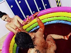 Lesbians with big fake tits enjoy wrestling in a pool of jello